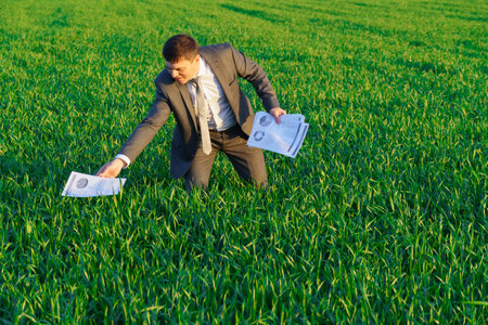 businessman lays out reports on a green grass field, the concept of work and freelancingの写真素材