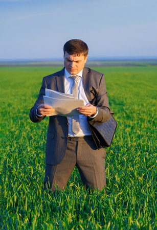 a businessman poses on a green grass field, concept of leisure or freelancingの写真素材