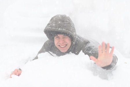 a boy lies in the snow, on a snowy street, it is snowing, a blizzard and frost on a winter day