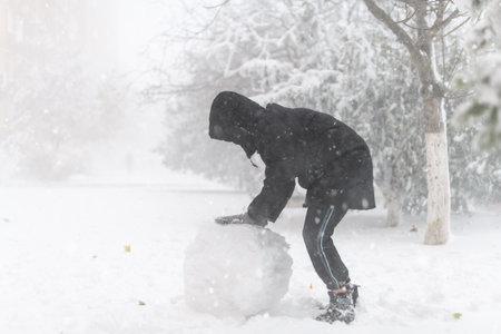 a girl is playing with snow on the street, it is snowing, a blizzard and frost on a winter day