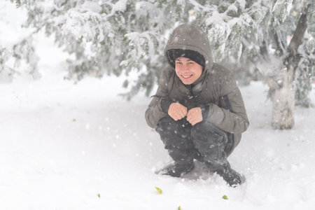 a boy is playing with snow on the street, it is snowing, a blizzard and frost on a winter dayの写真素材