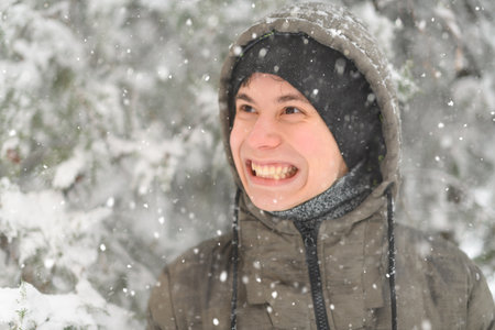 a boy is posing with snow on the street, it is snowing, a blizzard and frost on a winter dayの写真素材
