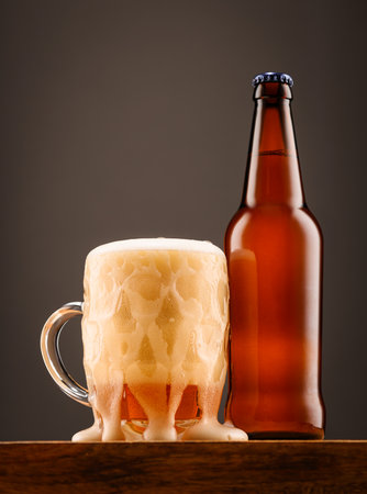 A bottle of beer and a glass of beer on a dark background.の写真素材