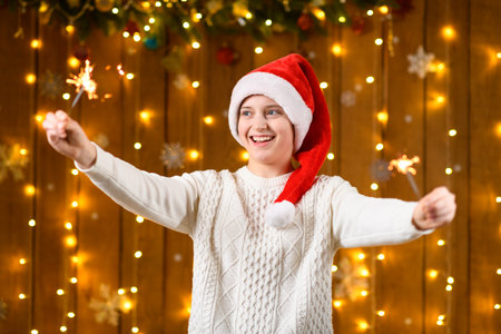 A teenage girl poses with sparklers, decorations for the New Year holiday, festive illumination and garlandsの写真素材
