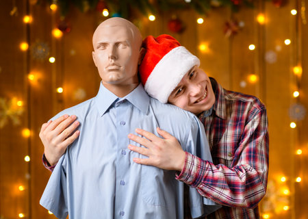 A teenage boy poses with a male mannequin as a friend in New Year decorations with festive illumination and garlands, Christmas lights and decorations, Holiday themeの写真素材
