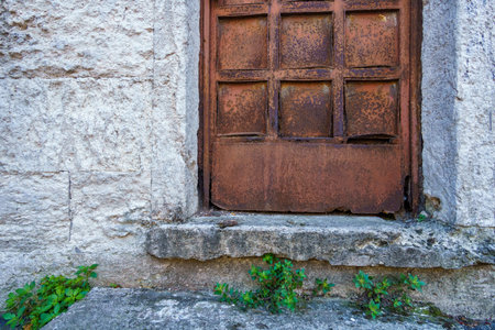 an old iron door with bars, rusty, and a white stone wallの写真素材