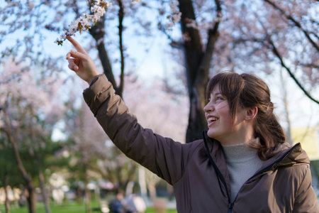 portrait of a teenage girl in a spring park touches flowers, flowering treesの写真素材