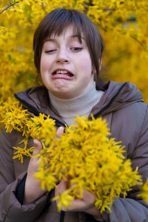 portrait of a girl on the background of yellow forsythia flowers, spring nature and blossomsの写真素材