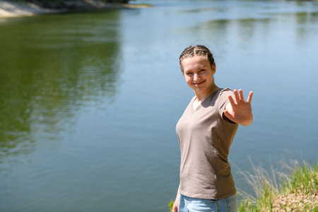 Teen girl relaxing on river bank, beautiful spring nature in forest, green leaves, landscapeの写真素材