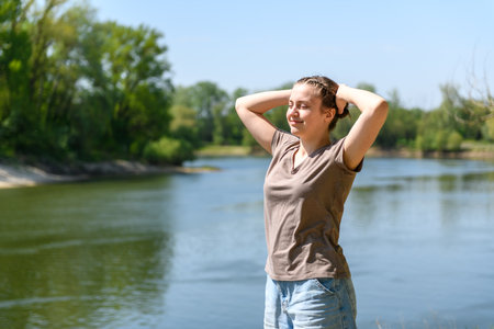 Teen girl relaxing on river bank, beautiful spring nature in forest, green leaves, landscapeの写真素材