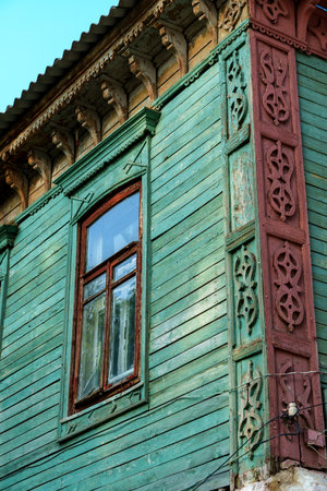 facade of an old building with window, wooden walls and windows painted with weathered green and brown paint, old architectureの写真素材