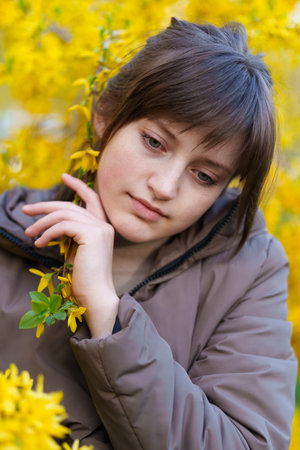 portrait of a girl on the background of yellow forsythia flowers, spring nature and blossomsの写真素材