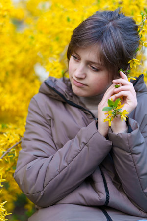 portrait of a girl on the background of yellow forsythia flowers, spring nature and blossomsの写真素材