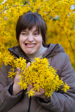 portrait of a girl on the background of yellow forsythia flowers, spring nature and blossomsの写真素材
