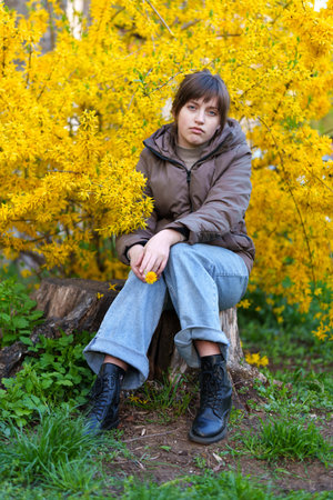 portrait of a girl on the background of yellow forsythia flowers, spring nature and blossomsの写真素材