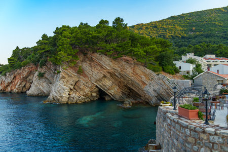 An outdoor cafe or restaurant overlooking the cliffs along the Adriatic Sea, with forests atop the peaks, surrounded by stunning nature in Petrovac, Montenegro.の写真素材