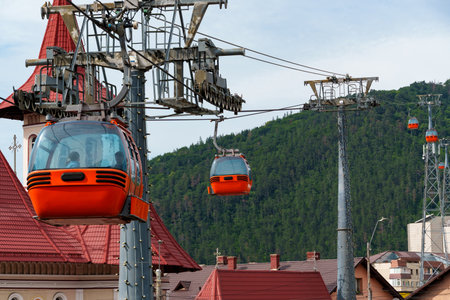 cabins of funicular, cable car, against background of hill and city, blue sky with white clouds