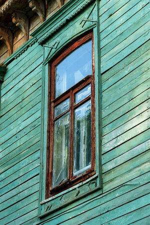 facade of an old building with window, wooden walls and windows painted with weathered green and brown paint, old architectureの写真素材