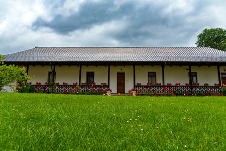 beautiful rural house decorated with flowers, in traditional Romanian or Moldovan style, against the backdrop of a green lawnの写真素材
