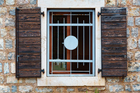 Old European architecture, view of the facade of a building in a town with stone walls and wooden shutters, on a bright sunny dayの写真素材