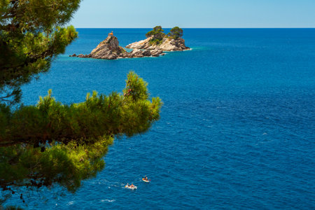 beautiful seascape, through the branches of trees, a view of sea and islands with a small church on top of a cliff, Petrovac, Montenegroの写真素材