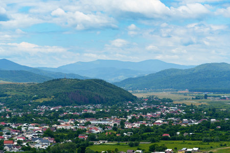 beautiful spring landscape, fields and village, Carpathian mountains on background, blue sky and white cloudsの写真素材