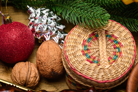 Woven basket and walnuts with red Christmas ball and pine branches on wooden backgroundの写真素材