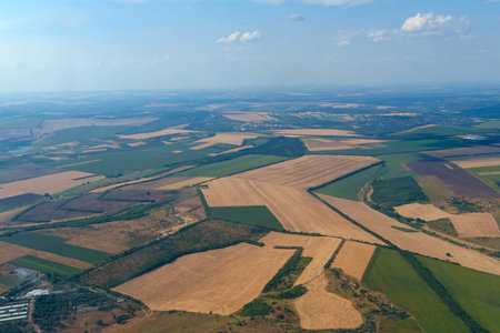 Aerial shot from airplane window overlooking patchwork of farming fields and rural countrysideの写真素材