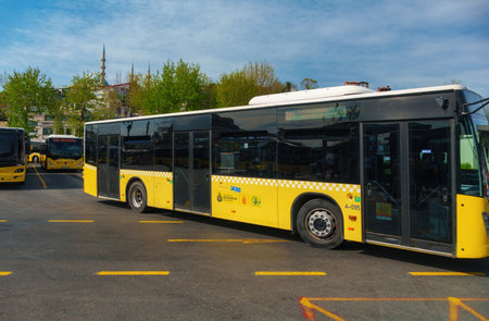 Istanbul, Turkey - May 8, 2026: Yellow public transit bus parked at a station in Istanbul, Turkey. Urban city transport and passenger transportation concept with cityscape background under a blue sky.