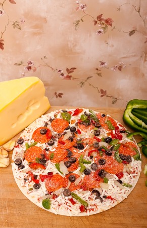 Raw pizza with pepperoni, bell peppers, black olives and onionsの写真素材
