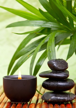 Balanced pebbles with aromatherapy candle and bamboo leavesの写真素材