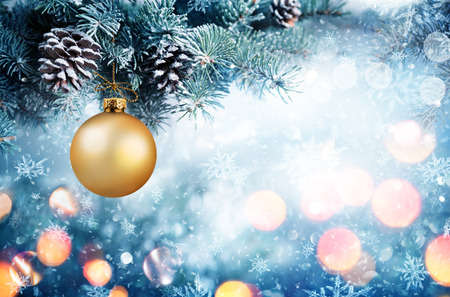 Golden Bauble Hanging Fir Branch With Snowfallの写真素材