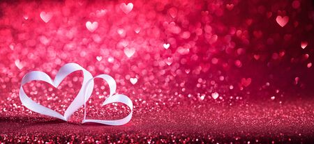 Valentines Day - Ribbon Shaped Hearts On Red Shiny Backgroundの写真素材