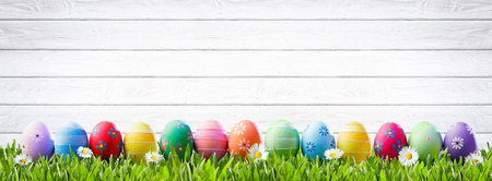 Easter Eggs In A Row And White Wooden Backgroundの写真素材