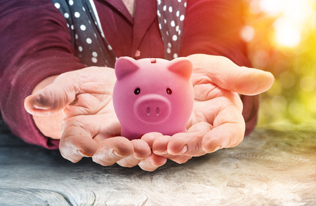Retirement Concept - Elderly Lady Holding A Piggy Bank At The Sunset Of Her Lifeの写真素材