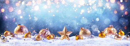 Golden Baubles On Snow With Christmas Lightsの写真素材