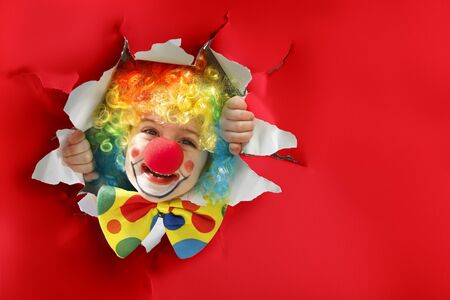 Child With Clown Costume Going Through A Paper Holeの写真素材