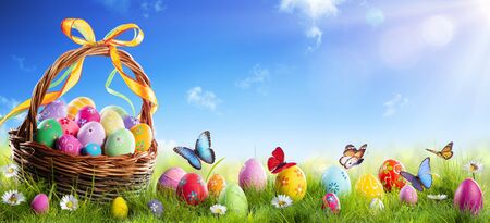 Easter Painted Eggs In Basket On Grass With Sunny Spring Backgroundの写真素材