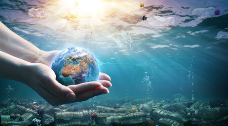 Plastic Waste In The Environment - Ocean Pollution- Hands Holding Earthの写真素材
