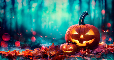 Jack O 'Lanterns On Red Leaves In Spooky Forest With Defocused Ghostsの写真素材