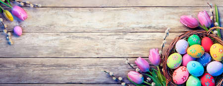 Easter Decoration - Painted Eggs In Basket With Tulips On Natural Wooden Plankの写真素材
