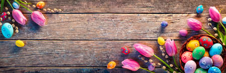 Easter Decoration - Painted Eggs In Vintage Basket On Rustic Table With Willows Branches And Tulipsの写真素材