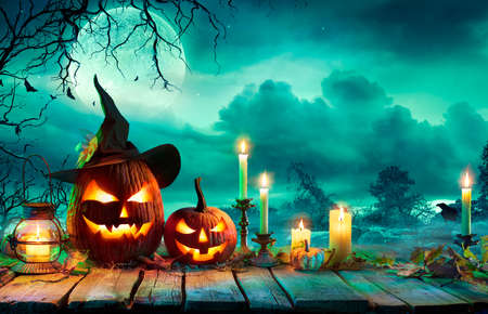 Halloween At Night - Pumpkins With Witch Hat And Candles On Table In Mystery Landscapeの写真素材
