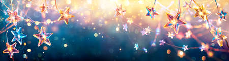 Christmas Stars With Golden Lights Hanging In Blue Background - String With Abstract Defocused Bokehの写真素材
