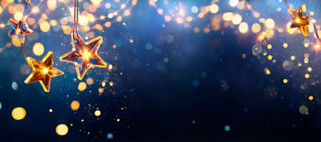 Christmas Stars Lights - Golden String Hanging In Blue Background With Abstract Defocused Bokehの写真素材