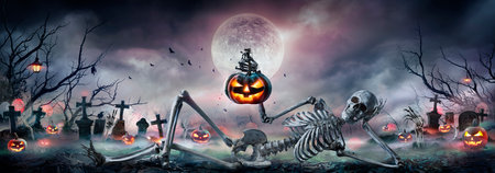 Halloween - Zombie Skeleton With Pumpkin In Hand Sitting On Cemetery At Night With Full Moonの写真素材
