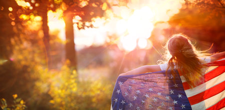 Independence Day - Little Girl With Usa American Flag - Freedom Concept - Defocused Abstract Sunset, Flare Effect And Motion Blurの写真素材