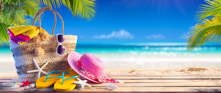 Summer Bag On Tropical Sand - Beach Vacation - Accessories Hat Towel And Flip Flops With Leaves Palm And Blue Seaの写真素材