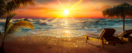Tropical Beach At Sunset - Deckchairs With Parasol With Glittering Light Effects - Abstract Defocused Background And Selective Focus In Foregroundの写真素材