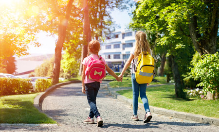 Students With Rucksacks Walking In The Park - Schoolgirls Return To Schoolの写真素材